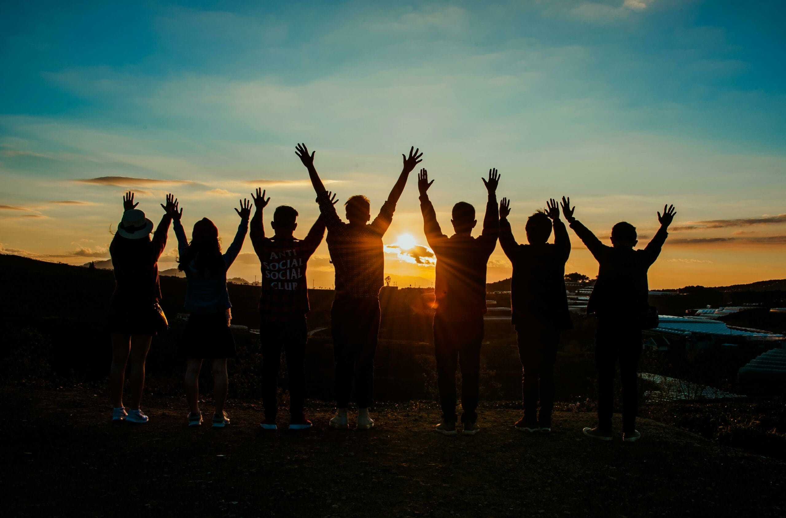 Imagen de un grupo de amigos con el atardecer de fondo
